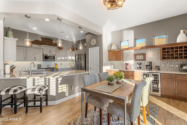 dining area with wine cooler, sink, and light wood-type flooring