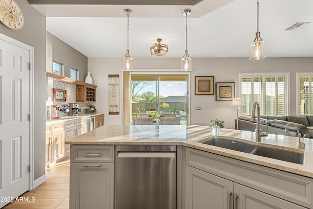 kitchen with sink, light stone counters, and decorative light fixtures