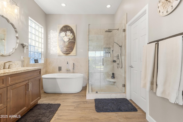 bathroom with hardwood / wood-style flooring, vanity, separate shower and tub, and tile walls