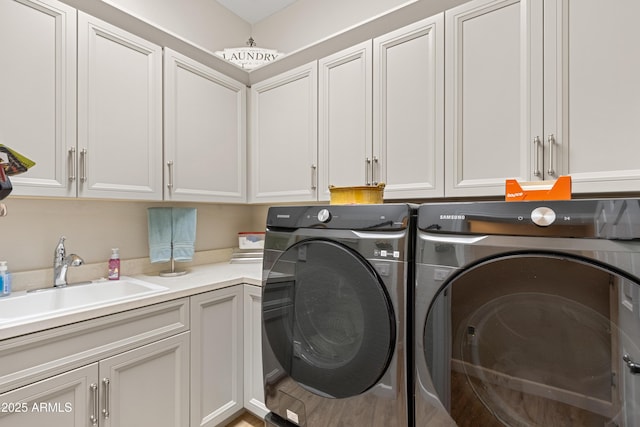 clothes washing area featuring cabinets, washer and clothes dryer, and sink