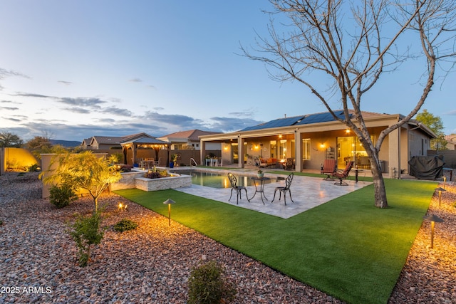 back house at dusk with a gazebo, a patio, and solar panels