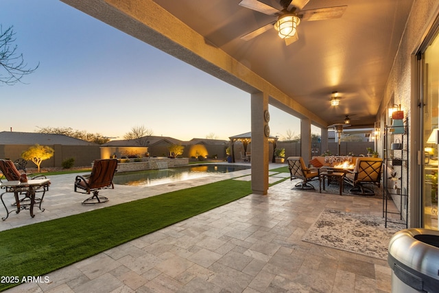 patio terrace at dusk with a fenced in pool and an outdoor fire pit