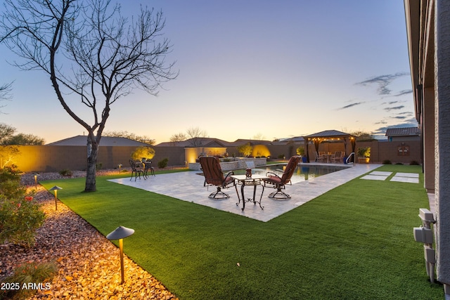 yard at dusk featuring a gazebo and a patio