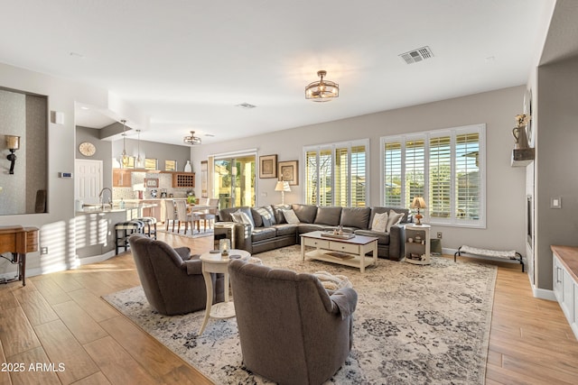 living room with plenty of natural light, sink, and light hardwood / wood-style flooring