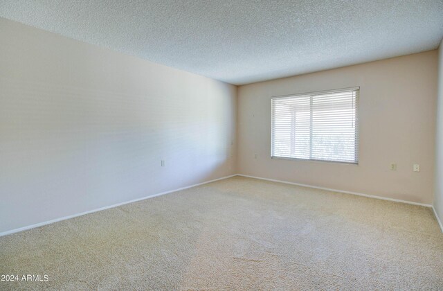 carpeted spare room with a textured ceiling and lofted ceiling with beams