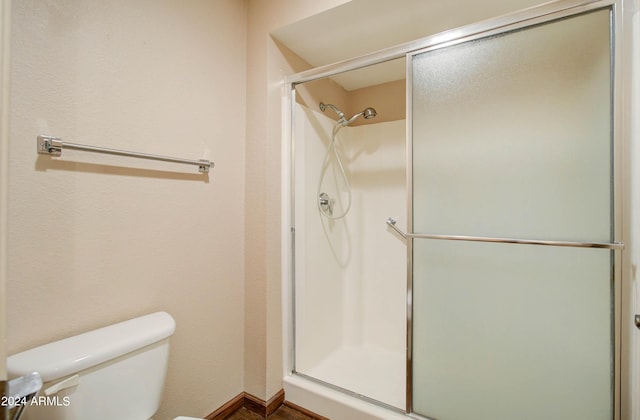 bathroom featuring a shower with shower door and toilet