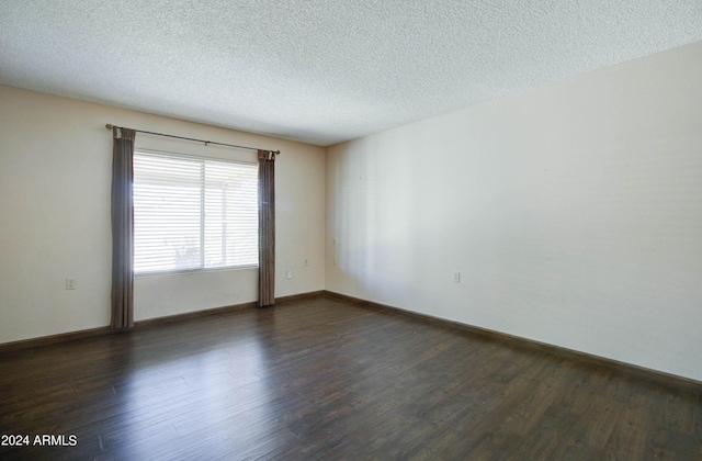 spare room featuring a textured ceiling and dark hardwood / wood-style flooring