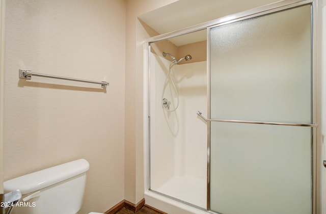 bathroom with a shower with door and toilet