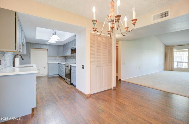 kitchen with tasteful backsplash, dark colored carpet, stainless steel appliances, decorative light fixtures, and sink