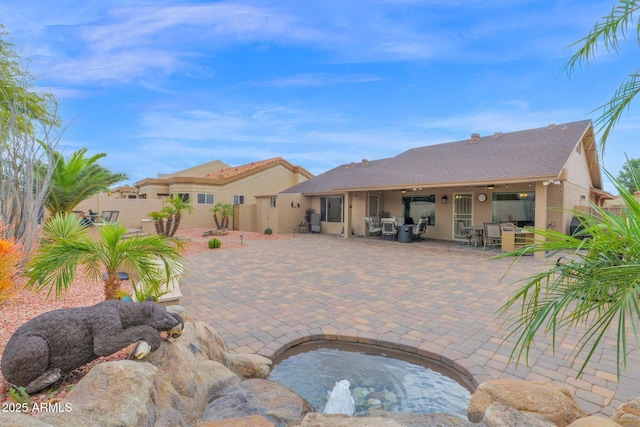 rear view of property featuring stucco siding, outdoor dining area, a patio, and fence