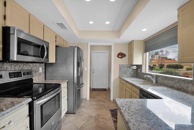 kitchen with visible vents, a sink, a tray ceiling, backsplash, and stainless steel appliances