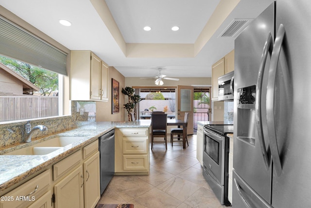 kitchen with a sink, cream cabinets, visible vents, and stainless steel appliances