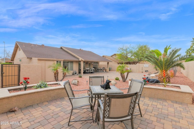 view of patio featuring outdoor dining space, a fenced backyard, and a gate