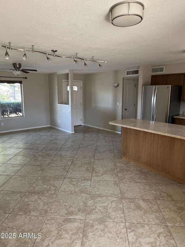 kitchen with light countertops, visible vents, freestanding refrigerator, open floor plan, and a textured ceiling