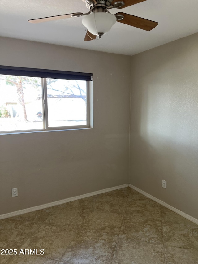 empty room featuring ceiling fan and baseboards