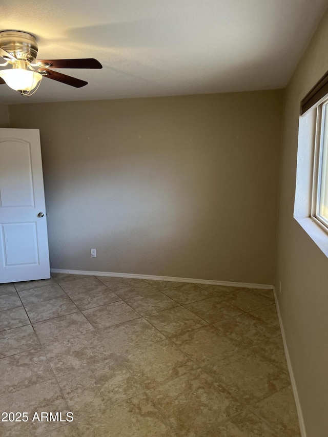 unfurnished room featuring a ceiling fan and baseboards