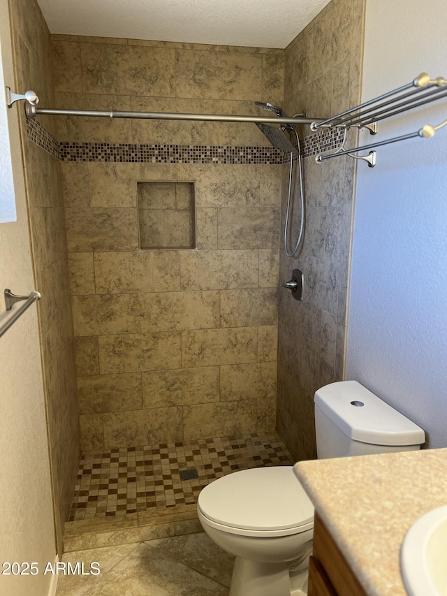 bathroom with a tile shower, vanity, and toilet