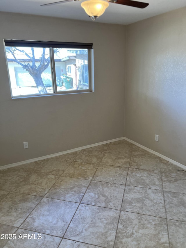 empty room featuring baseboards, a ceiling fan, and tile patterned floors