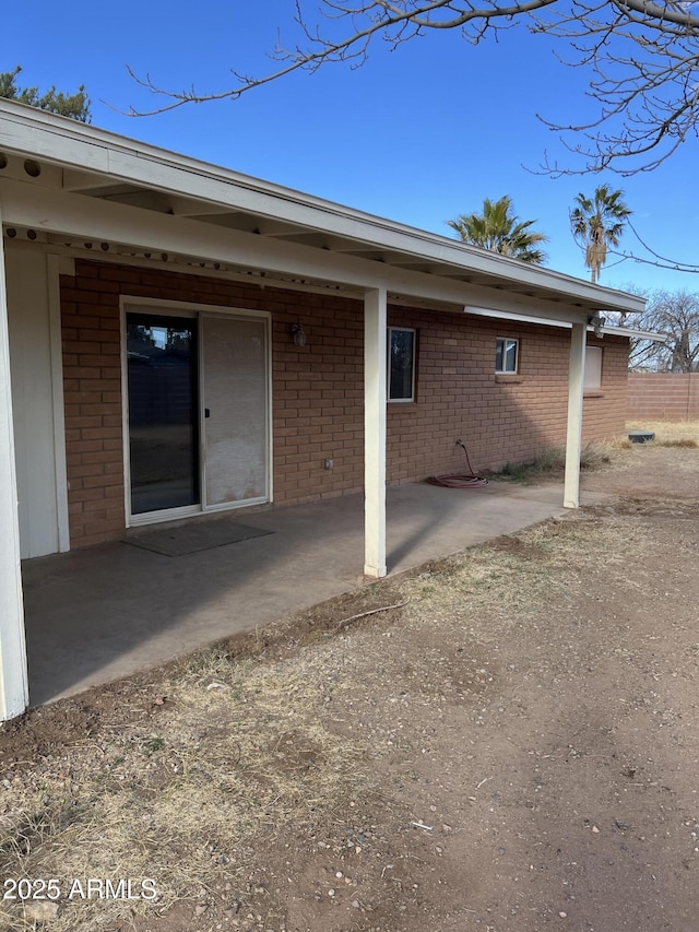 exterior space with brick siding and a patio