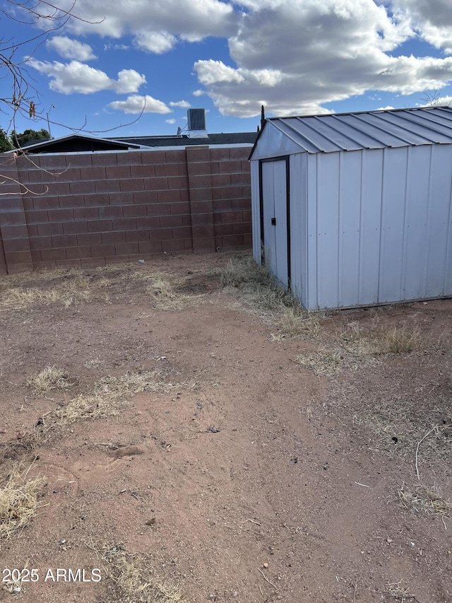 view of yard featuring an outbuilding, cooling unit, fence, and a storage shed