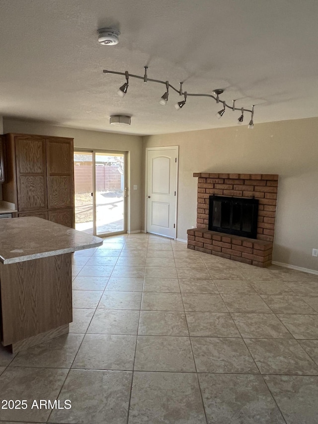 unfurnished living room with a fireplace, a textured ceiling, baseboards, and tile patterned floors