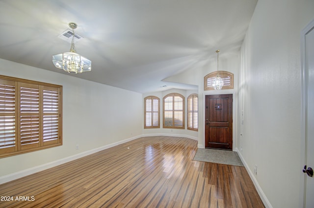 foyer with hardwood / wood-style flooring, lofted ceiling, and a chandelier