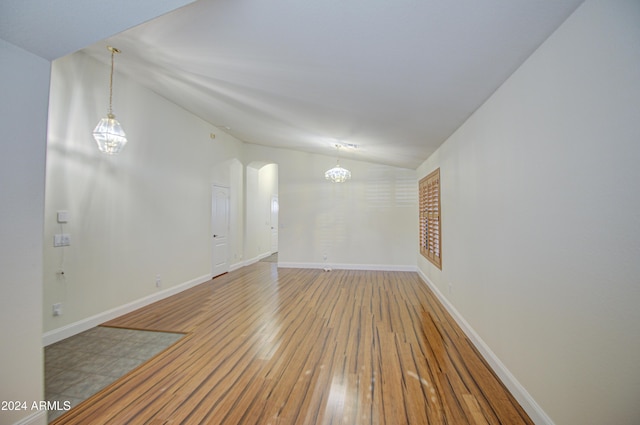 spare room featuring vaulted ceiling and wood-type flooring