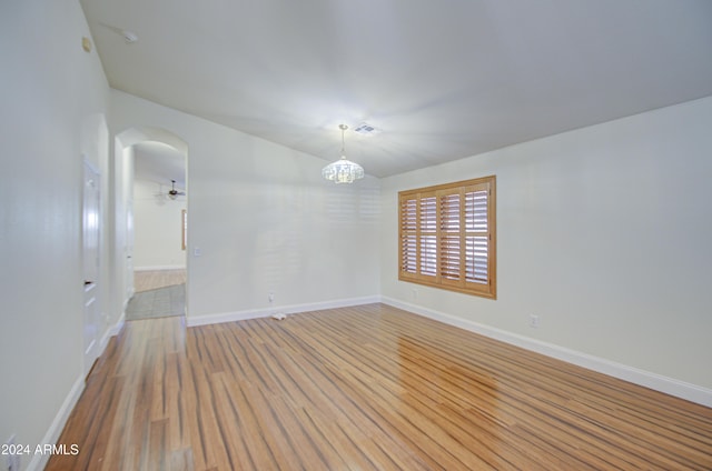 unfurnished room with light wood-type flooring and a notable chandelier