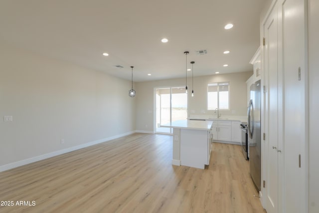 kitchen with light wood-type flooring, a center island, white cabinets, and recessed lighting