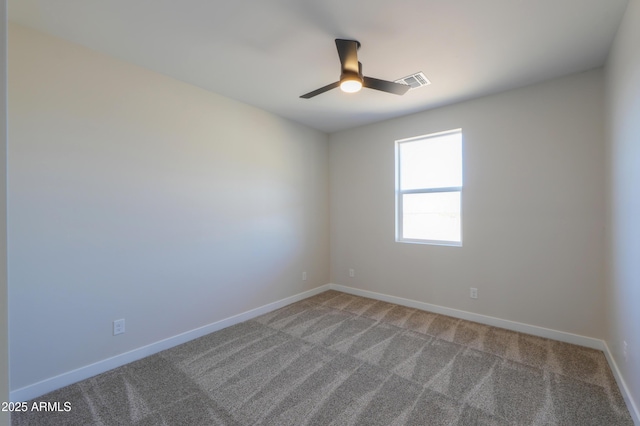 carpeted spare room featuring a ceiling fan, visible vents, and baseboards