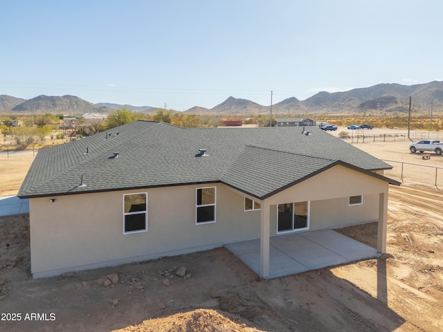 back of property featuring a shingled roof, a patio area, a mountain view, and stucco siding