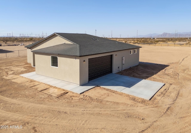 view of front of house featuring driveway, a shingled roof, a garage, and stucco siding