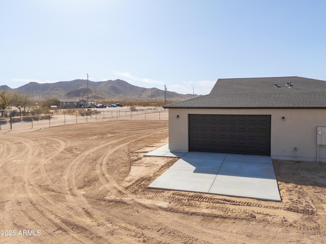 exterior space with concrete driveway, a mountain view, and fence