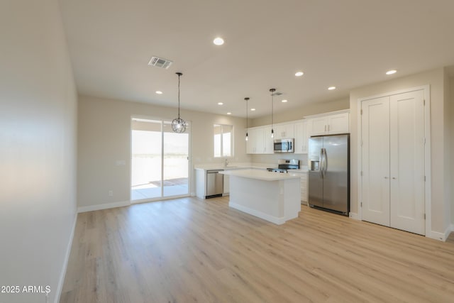 kitchen with visible vents, white cabinets, light wood-style flooring, a center island, and stainless steel appliances