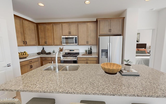 12550 W Luxton Ln, Avondale, AZ 85323 - kitchen with appliances with stainless steel finishes, a breakfast bar, recessed lighting, light stone countertops, and brown cabinetry