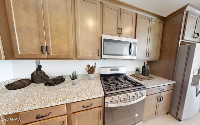 12550 W Luxton Ln, Avondale, AZ 85323 - kitchen featuring stainless steel appliances, light stone countertops, and light tile patterned floors