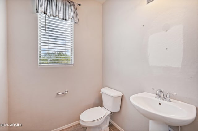 bathroom with toilet, sink, and wood-type flooring