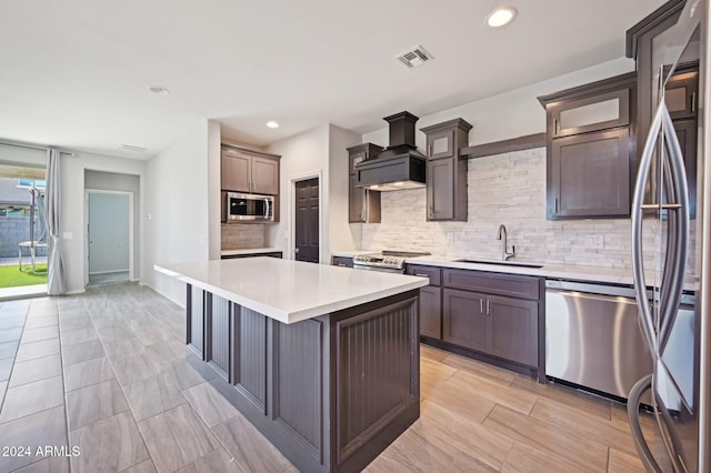 kitchen with stainless steel appliances, sink, custom range hood, a kitchen island, and backsplash