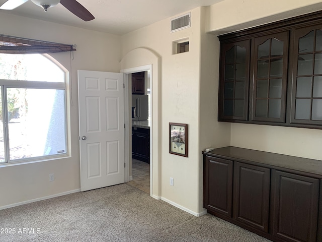 interior space featuring light carpet, ceiling fan, visible vents, and baseboards