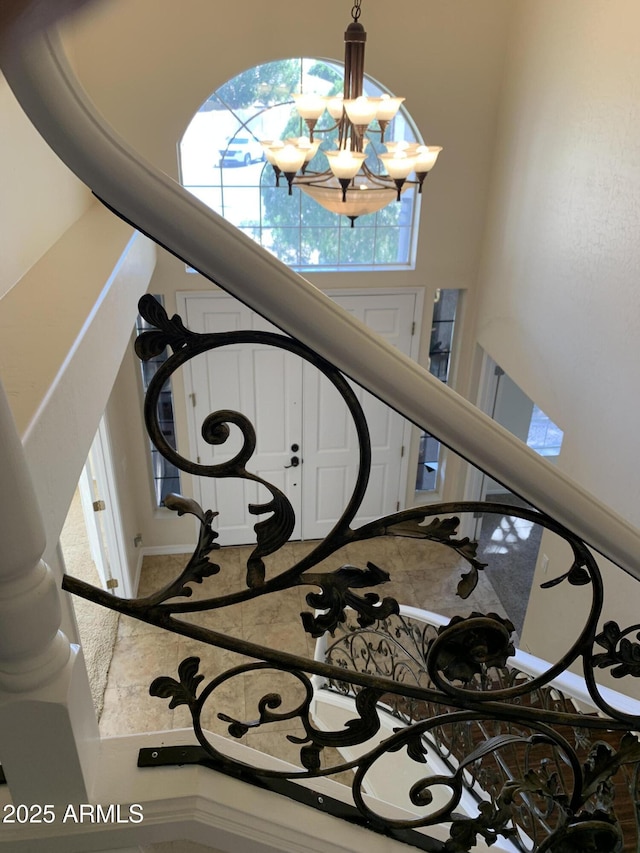 staircase with a high ceiling and a notable chandelier
