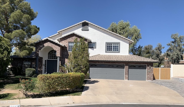 traditional-style home with brick siding, stucco siding, concrete driveway, a garage, and a tiled roof