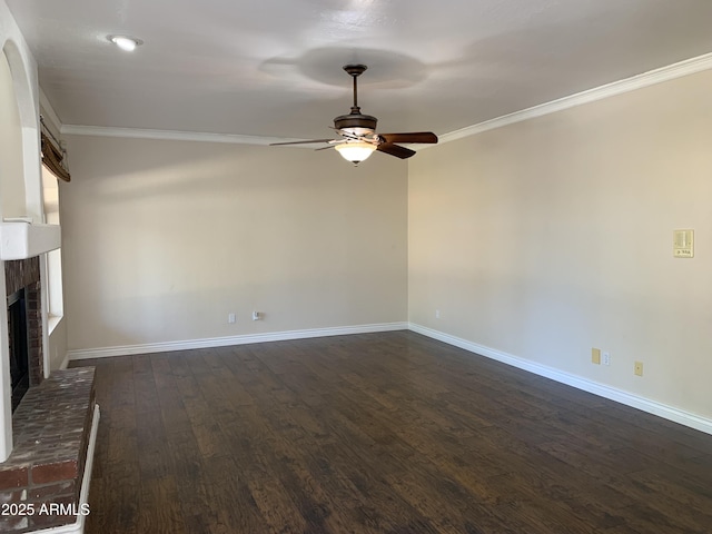 unfurnished living room featuring dark wood-style floors, a brick fireplace, baseboards, and crown molding