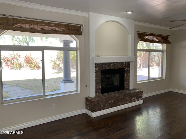 unfurnished living room with ornamental molding, a brick fireplace, baseboards, and wood finished floors