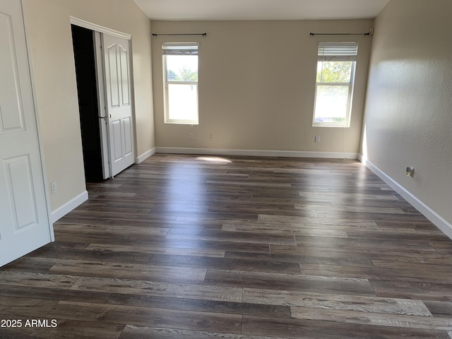 unfurnished bedroom with dark wood-style flooring, multiple windows, and baseboards