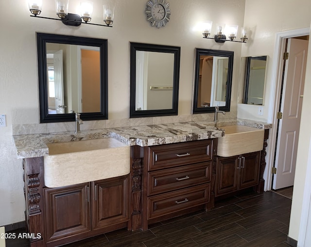 bathroom featuring wood tiled floor, a sink, and double vanity