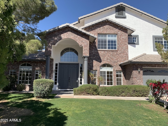 view of front of property with brick siding, a front lawn, a tile roof, and stucco siding