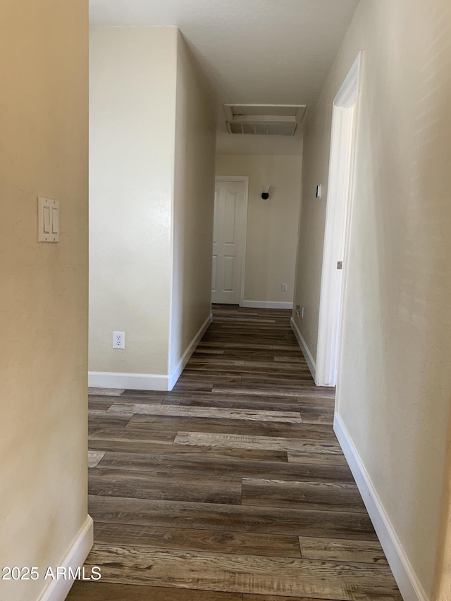 hallway featuring dark wood-style floors, visible vents, and baseboards