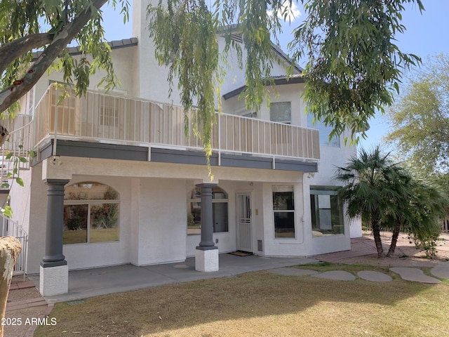back of property featuring a balcony, a patio, and stucco siding