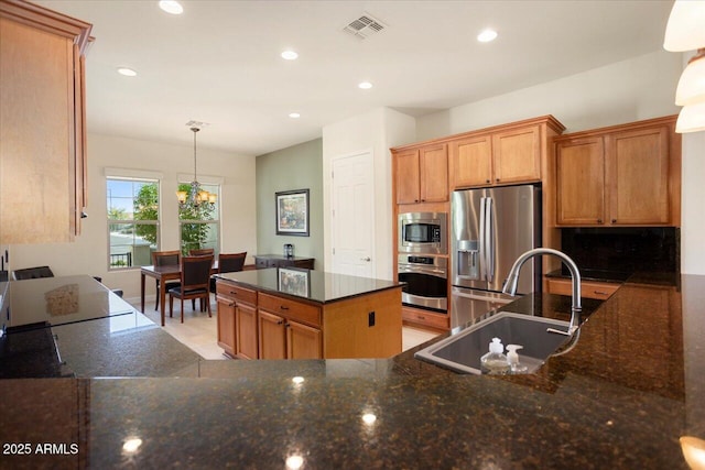 kitchen featuring sink, a center island, dark stone counters, pendant lighting, and stainless steel appliances