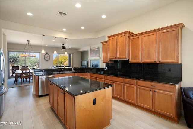 kitchen featuring sink, tasteful backsplash, stainless steel dishwasher, kitchen peninsula, and pendant lighting